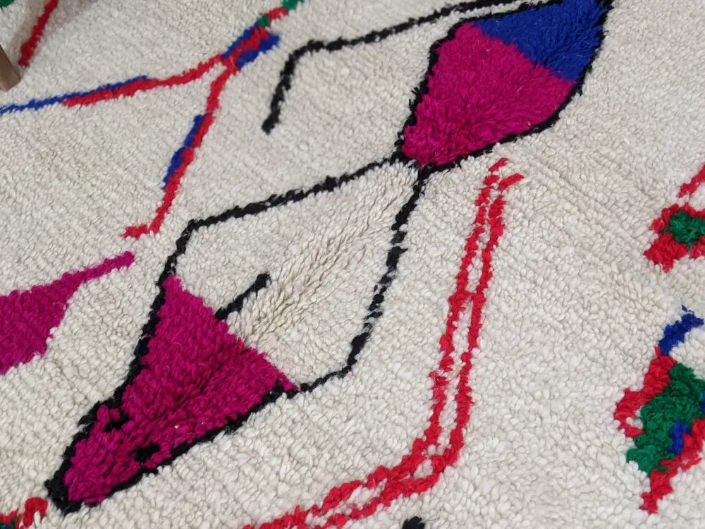 A plush white moroccan handmade azilal rug with bold magenta red blue and green geometric patterns in pure natural wool