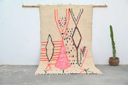 Beige moroccan handmade traditional azilal rug with vibrant pink green red and black geometric patterns by decorbites
