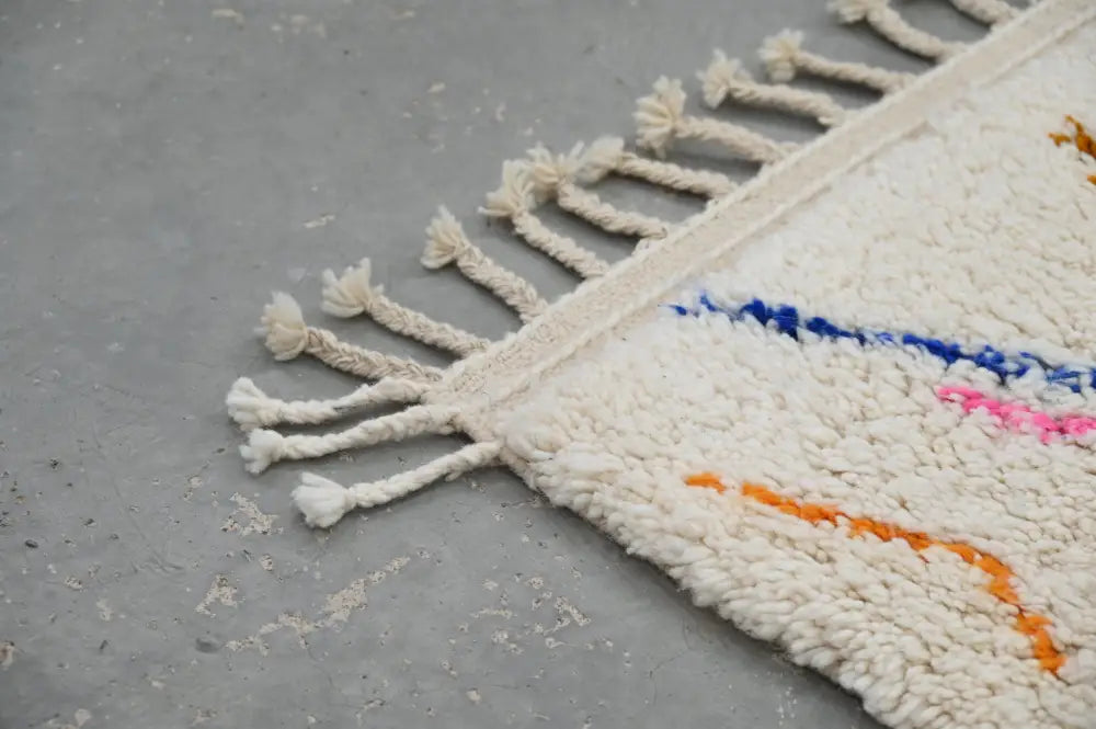 Cream-colored moroccan handmade traditional azilal rug with fluffy texture and colorful blue pink orange geometric patterns