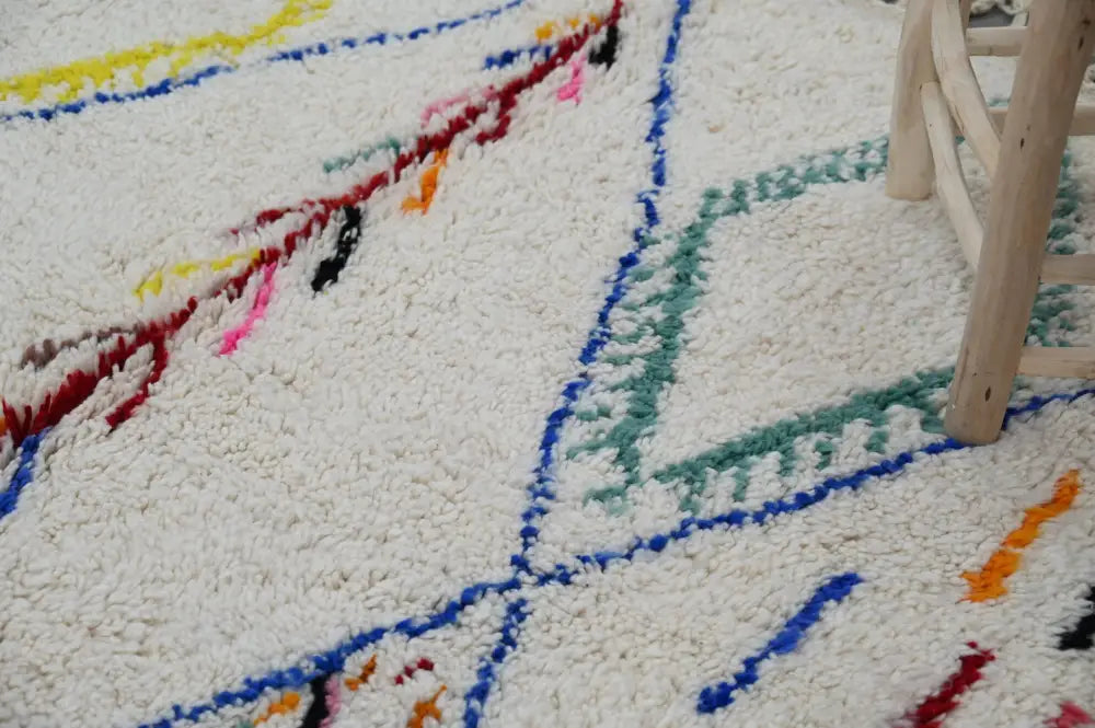 A plush white moroccan handmade traditional azilal rug with vibrant hand-knotted geometric patterns in multiple colors