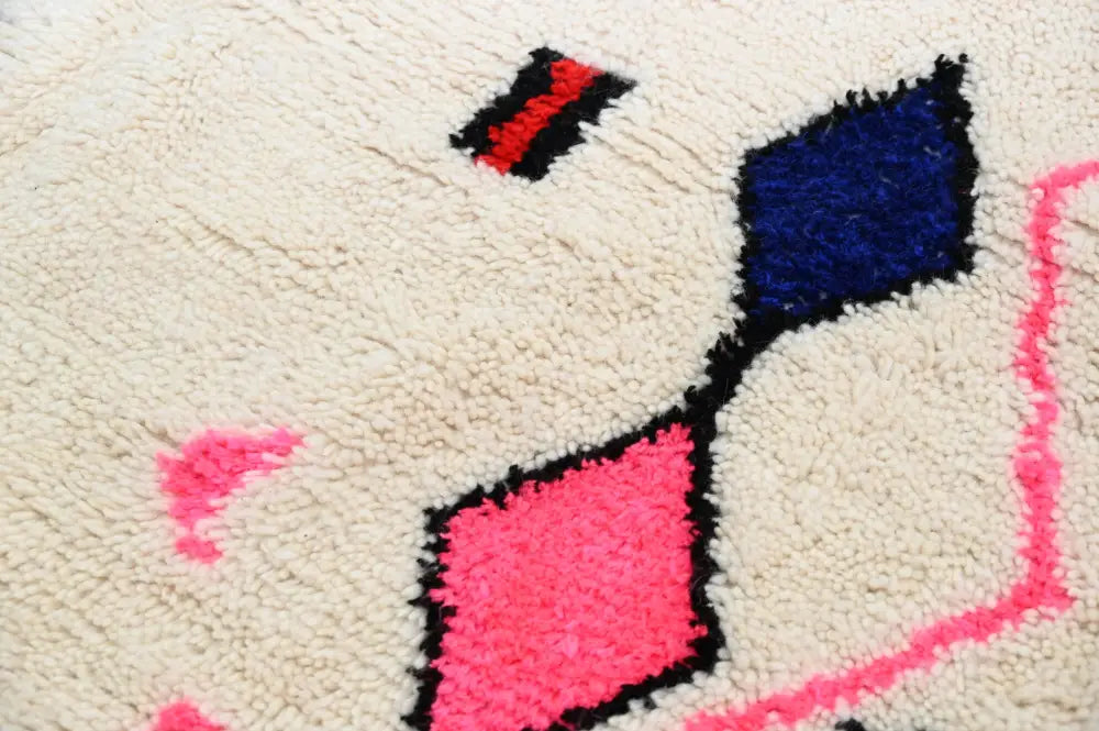 Cream-colored wool moroccan handmade traditional azilal rug with bold pink blue and black geometric patterns 273 x 151 cm