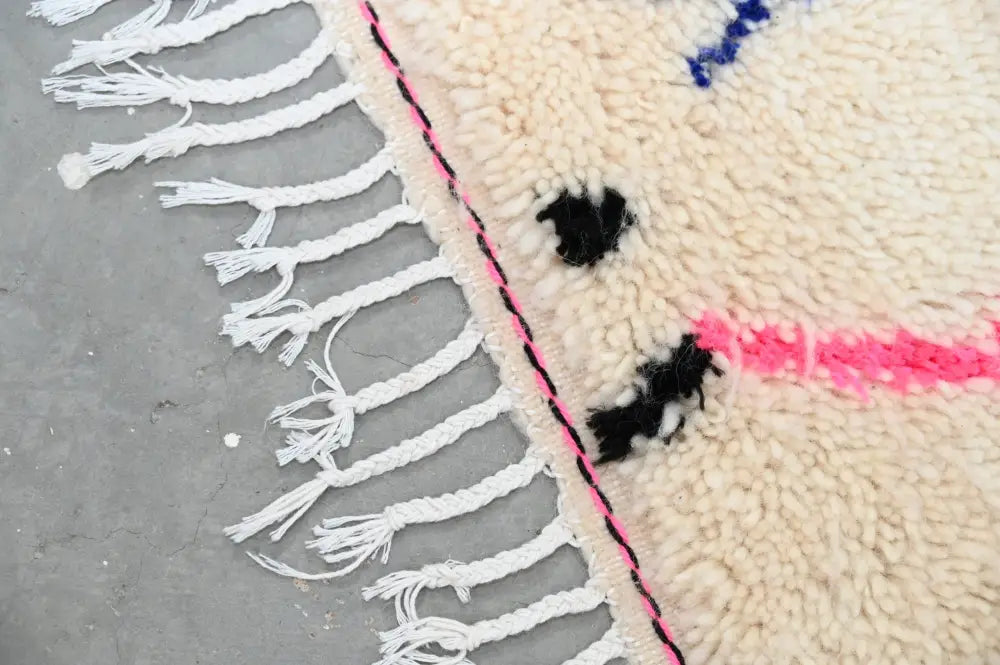 Cream-colored DecorBites™ moroccan handmade traditional azilal rug with white fringe and pink black geometric accents