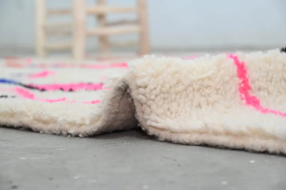 Cream-colored plush wool moroccan handmade traditional azilal rug with vibrant pink and blue geometric patterns