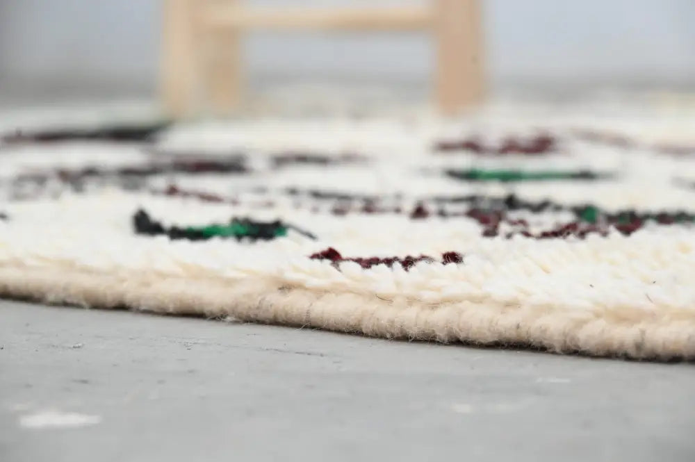 Cream-colored moroccan handmade traditional azilal rug with intricate black green and burgundy geometric wool patterns