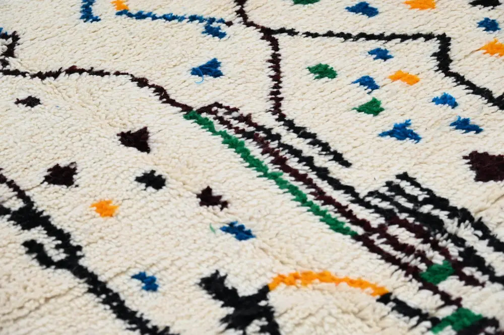 Cream-colored moroccan handmade traditional azilal rug with bold black green and orange geometric patterns 273 x 155 cm
