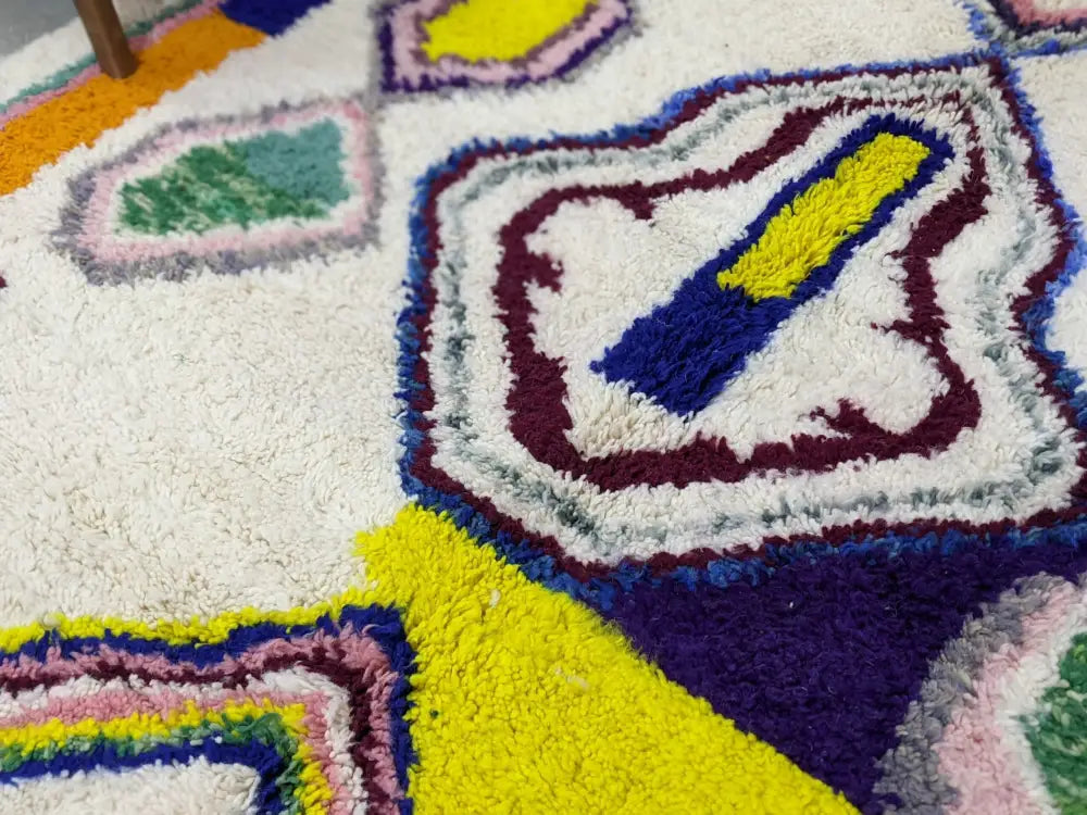 A plush moroccan handmade traditional azilal rug with shaggy texture and vibrant geometric patterns in yellow purple and green