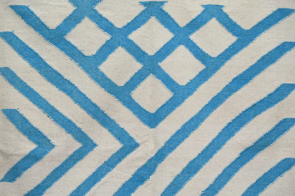 A cream-colored DecorBites™ moroccan handmade traditional azilal rug featuring bold blue geometric diamonds and stripes