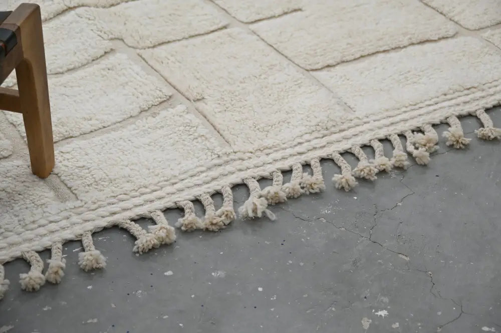 Cream-colored plush rectangular beni ouarain carpet with textured stone-like pattern and soft tassels, moroccan handmade