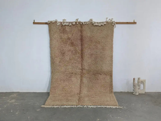 Beige plush wool beni ouarain rug with fringed edges hanging on wooden rod from decorbites traditional collection