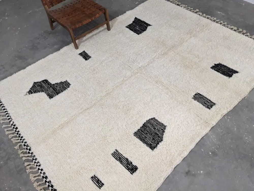 Cream-colored beni ouarain rug featuring black geometric patterns and fringed edges moroccan handmade 290 x 210 cm