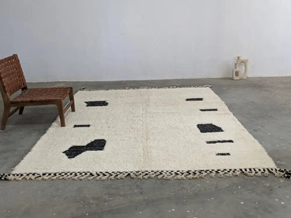 Cream-colored beni ouarain rug with black geometric patterns and fringed edges moroccan handmade traditional design