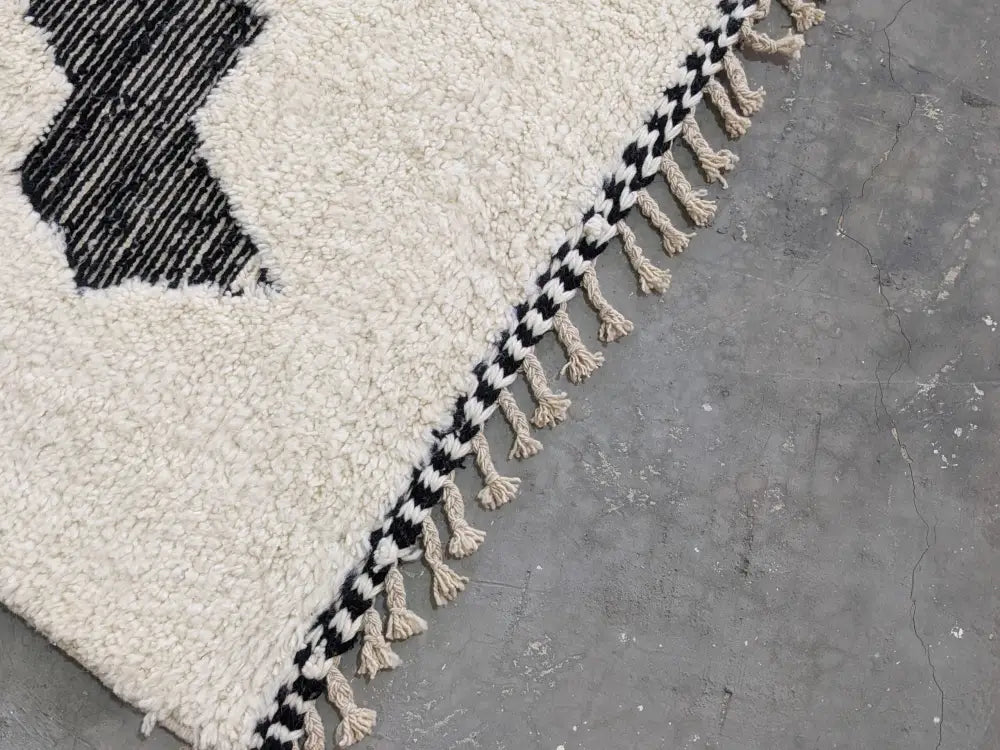 Cream-colored plush wool beni ouarain rug with bold black geometric pattern and fringe moroccan handmade design