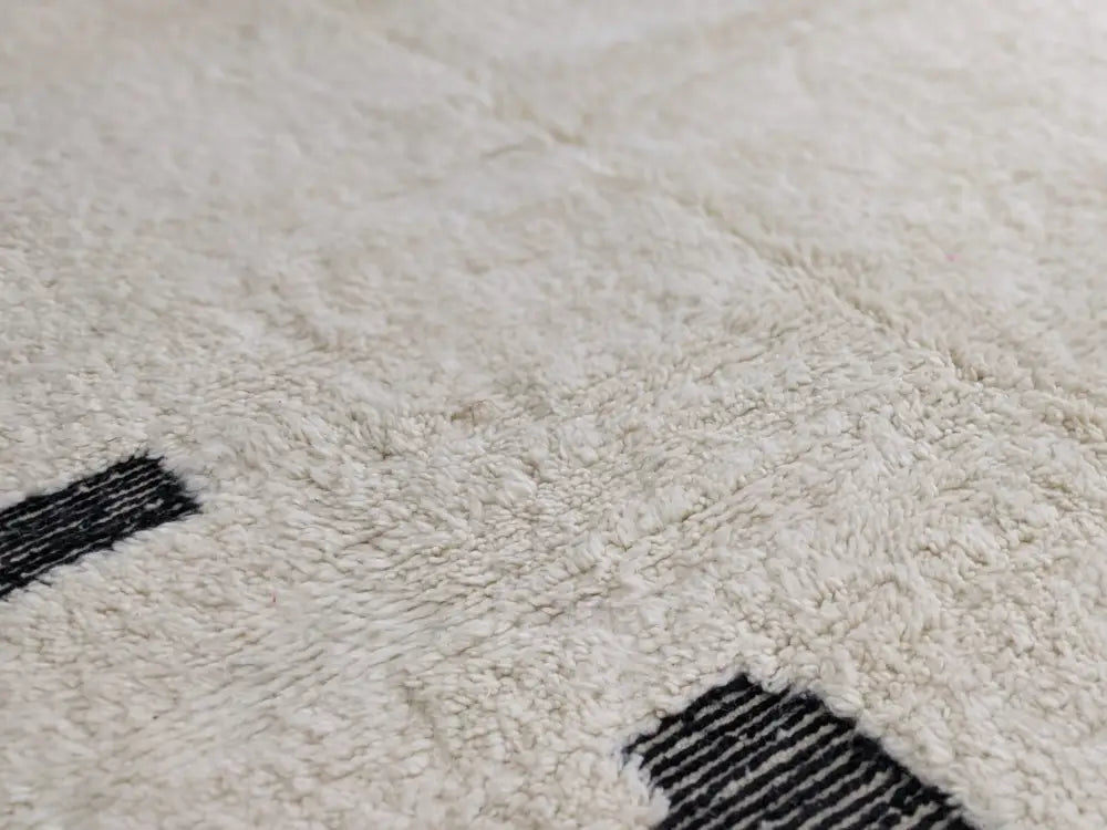 Cream-colored beni ouarain rug with bold black geometric stripes made from plush wool moroccan handmade design