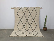 Cream-colored beni ouarain rug with black geometric diamond patterns and fringed edges moroccan handmade traditional design