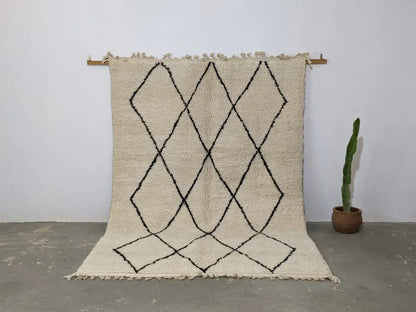 Cream-colored beni ouarain rug with black geometric diamond patterns and fringed edges moroccan handmade traditional design