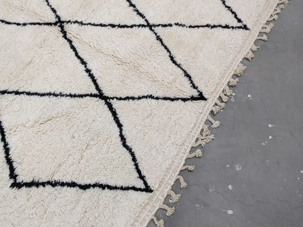 Cream-colored beni ouarain rug with bold black geometric patterns and fringed edges moroccan handmade traditional design