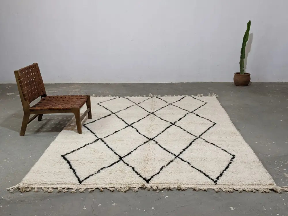 Cream-colored moroccan handmade beni ouarain rug with bold black diamond grid pattern and fringed edges 292 x 202 cm