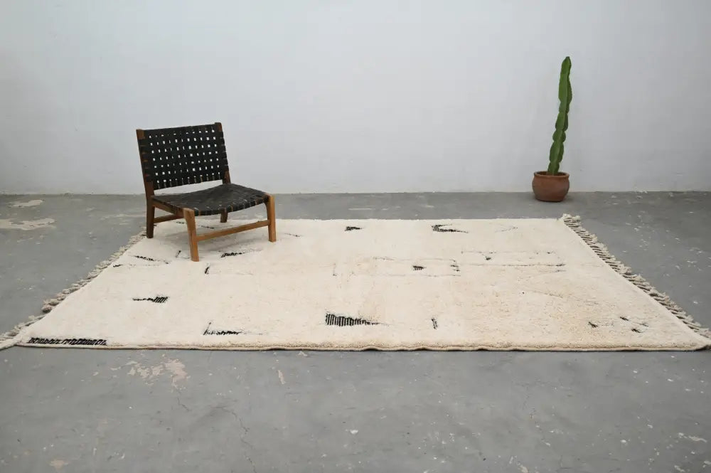 Cream-colored moroccan handmade beni ouarain rug with black abstract markings and fringed edges 300 x 200 cm