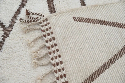 Cream-colored woven beni ouarain rug with brown geometric patterns and braided fringe moroccan handmade traditional design