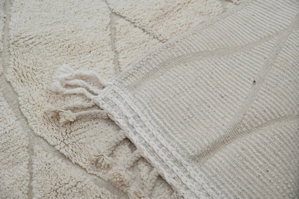 Cream-colored textured moroccan handmade beni ouarain rug with woven geometric patterns and fringed edges 300 x 211 cm