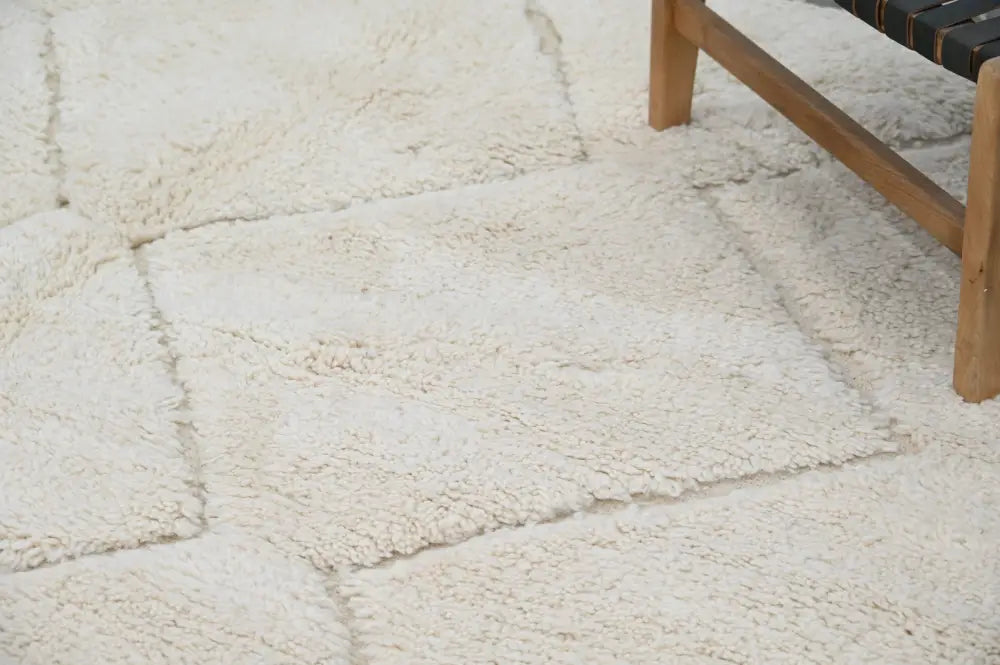 Cream-colored moroccan handmade beni ouarain rug with plush sheepskin texture and visible seams between square sections