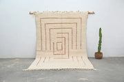 Cream-colored beni ouarain rug with geometric red-brown pattern and fringed edges moroccan handmade wool decor