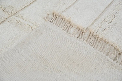 Cream-colored textured wool beni ouarain rug with fringed edges in 303 x 205 cm by DecorBites™
