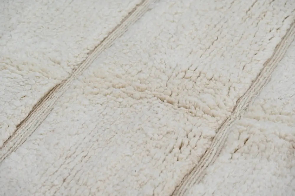 Cream-colored plush fleece bath towel with soft texture and woven stripes featured with beni ouarain rug design
