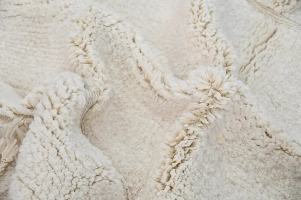 Cream-colored plush shearling beni ouarain rug with soft textured surface and decorative braided trim by decorbites
