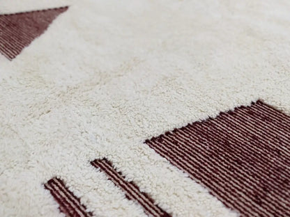 A plush white beni ouarain rug with geometric maroon patterns in a moroccan handmade textured high pile design