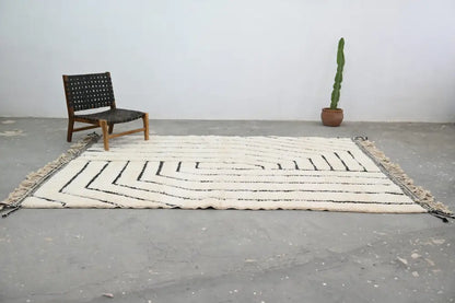 Cream-colored beni ouarain rug with black geometric zigzag patterns and fringed edges moroccan handmade wool rug