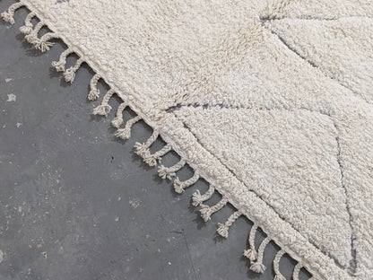 Cream-colored moroccan handmade beni ouarain rug with plush wool texture and decorative tassels on edges 305 x 204 cm