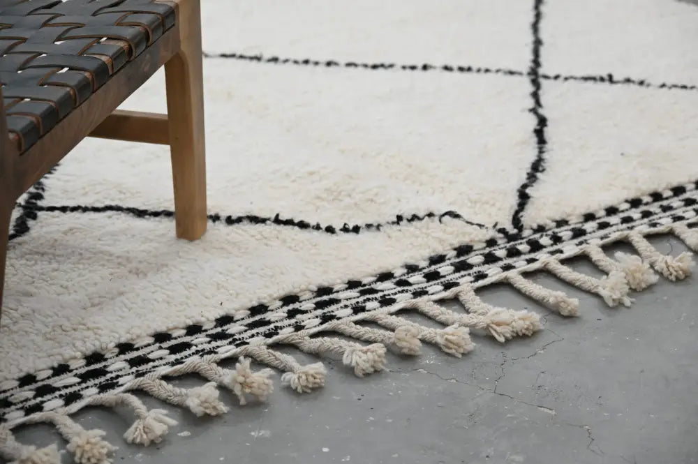 Cream-colored moroccan handmade beni ouarain rug with black geometric pattern and tassels by decorbites 309 x 204 cm