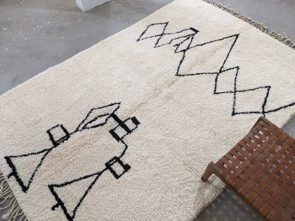 Cream-colored moroccan handmade beni ouarain rug with black geometric patterns and fringed edges 310 x 210 cm