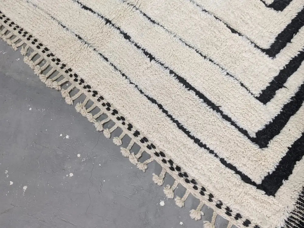 Cream-colored plush wool beni ouarain rug with bold black geometric stripes and decorative tassels moroccan handmade