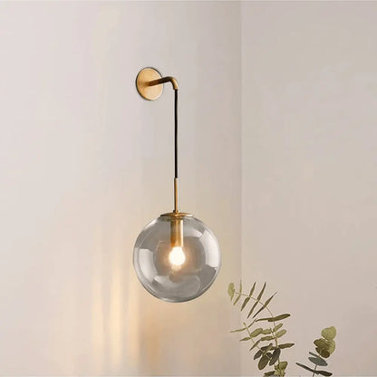 Decorbites™ moroccan modern wall sconce featuring a smoked glass globe and brass-finished metal arm with black cord suspension