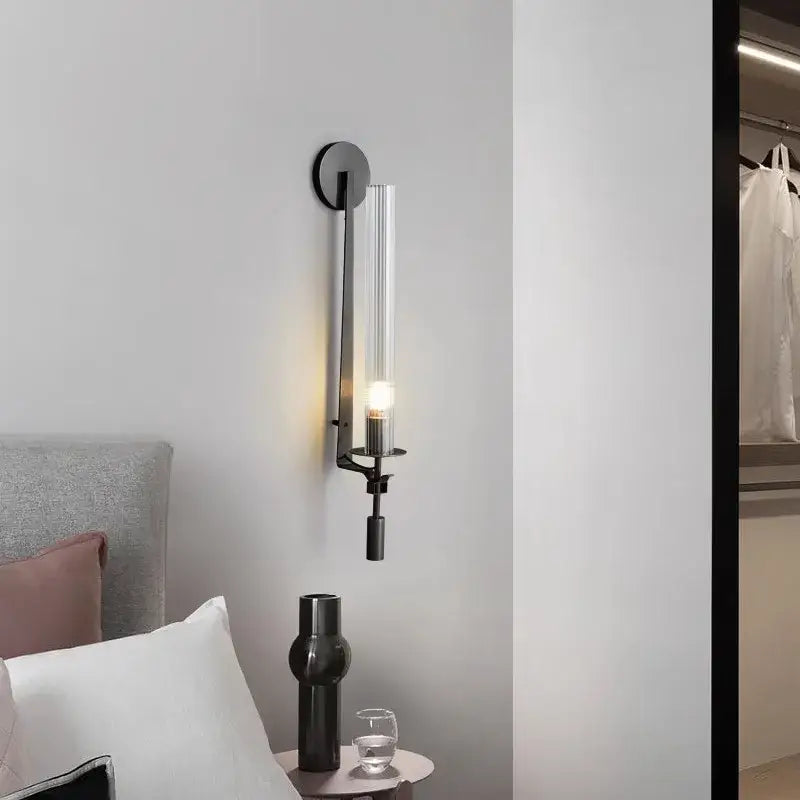 Modern black metal wall sconce with clear glass cylinder and warm light ideal for wall sconces and gold wall sconces decor