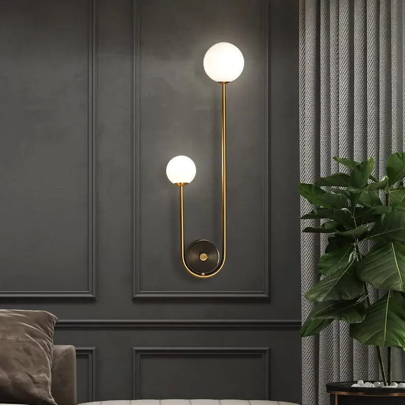 Traditional gold wall sconces featuring a gold wall design with two frosted glass globes and a curved metallic arm