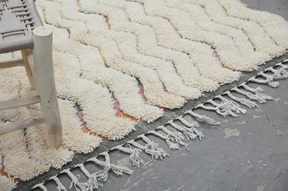 Cream-colored plush wool azilal rug with a zigzag pattern and fringed edges in a 240x147cm traditional azilal design
