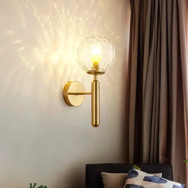 Gold-toned mynte wall sconce by decorbites featuring a faceted clear glass globe for elegant lighting