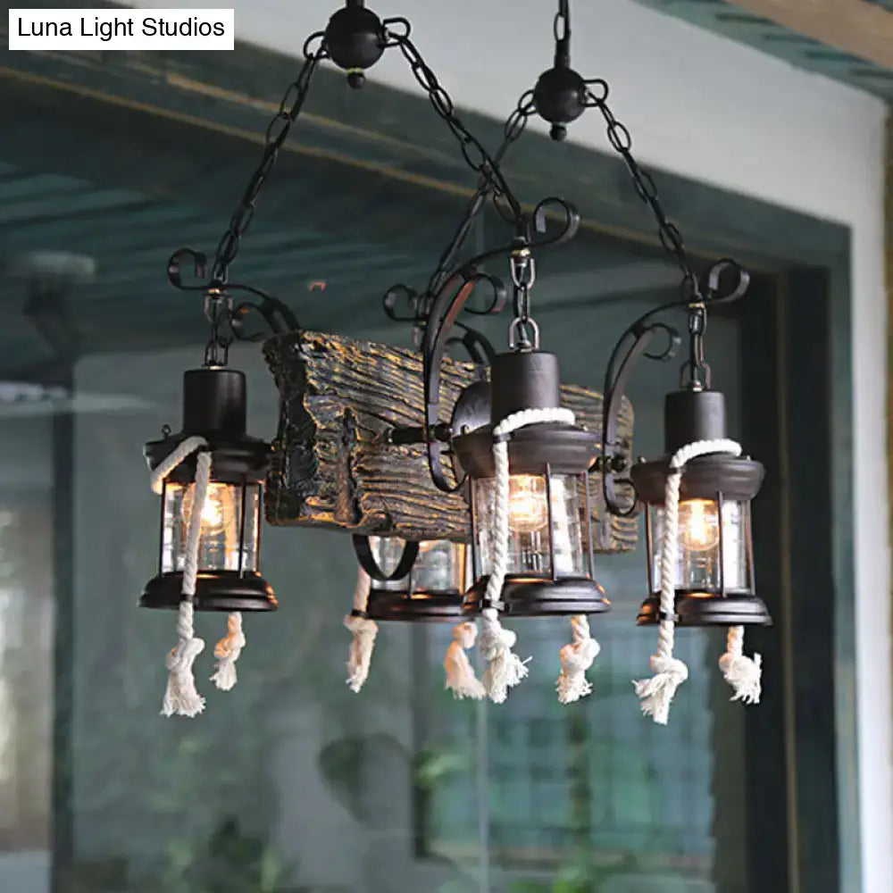 Black wrought iron island lamp with three lantern-style lights, glass enclosures, white hemp rope tassels, and bulb base design
