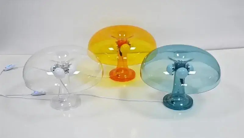 Three translucent led mushroom table lamps in clear yellow orange and blue with sleek metallic bases for modern decor