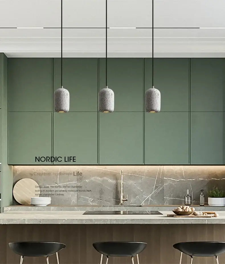 Three gray speckled cement pendant lamps with an industrial style hang above the kitchen counter by DecorBites