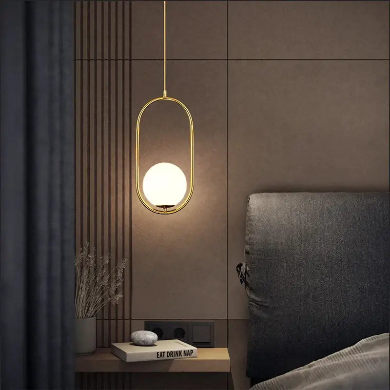 Gold-toned nordic pendant light featuring a frosted glass ball as the light source for modern decor