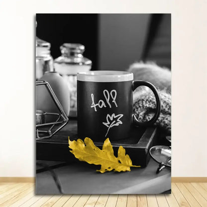 Black ceramic mug with white fall lettering and leaf design beside a yellow autumn leaf in nordic landscape canvas print set