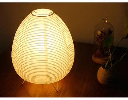 Warmly glowing egg-shaped led table lamp with metallic rim and slender wire legs for bedside or study lighting