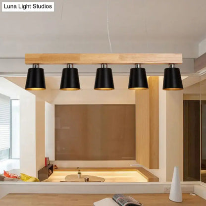 Modern black conical pendant lights with gold metal lampshade interiors mounted on a light wood beam for work rooms