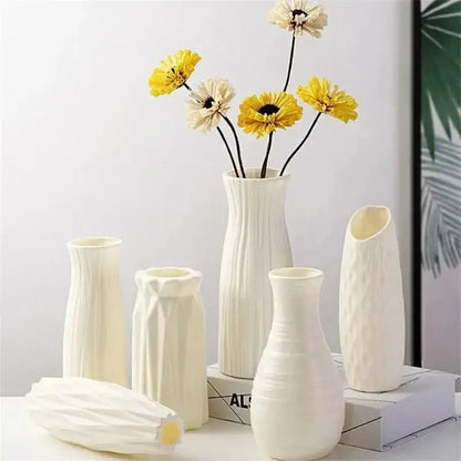 A collection of white nordic plastic vases with geometric textures arranged with dried yellow and cream flowers for modern decor