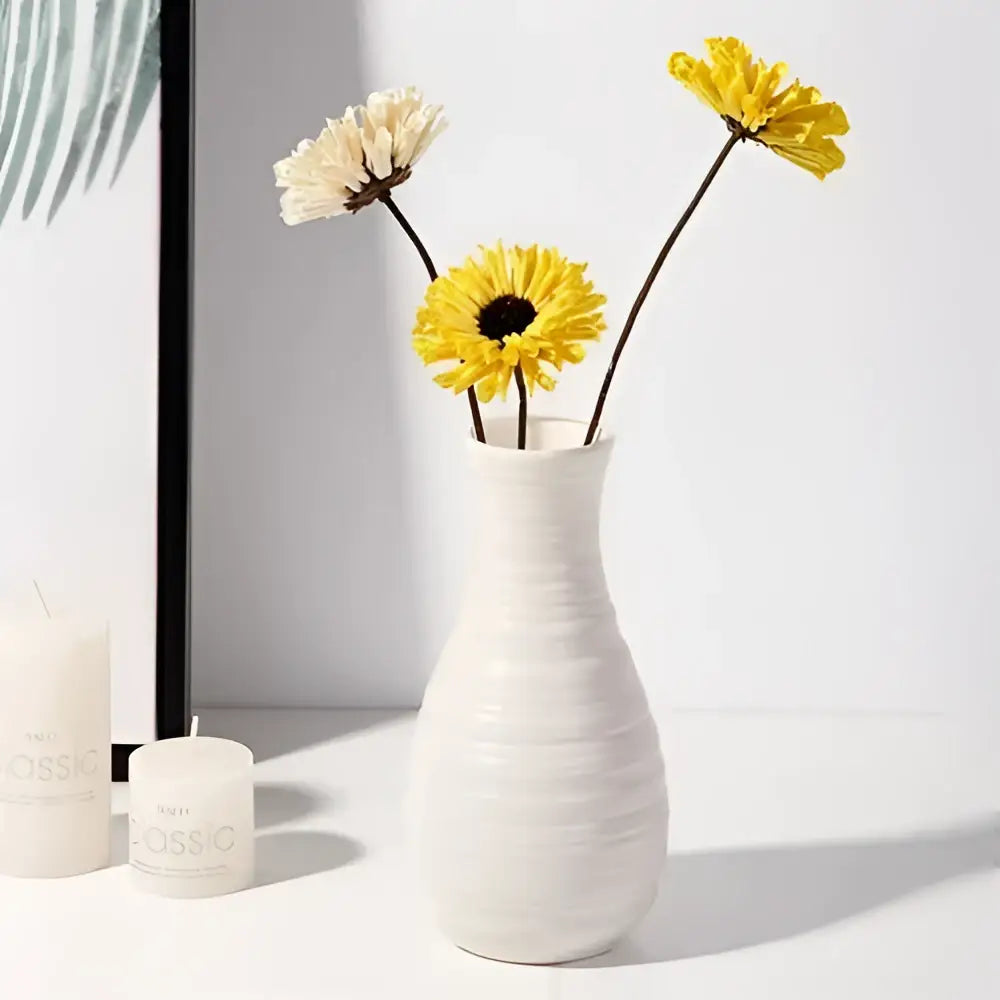 A sleek white nordic plastic vase with a ribbed texture holds yellow and cream dried flowers for modern decor