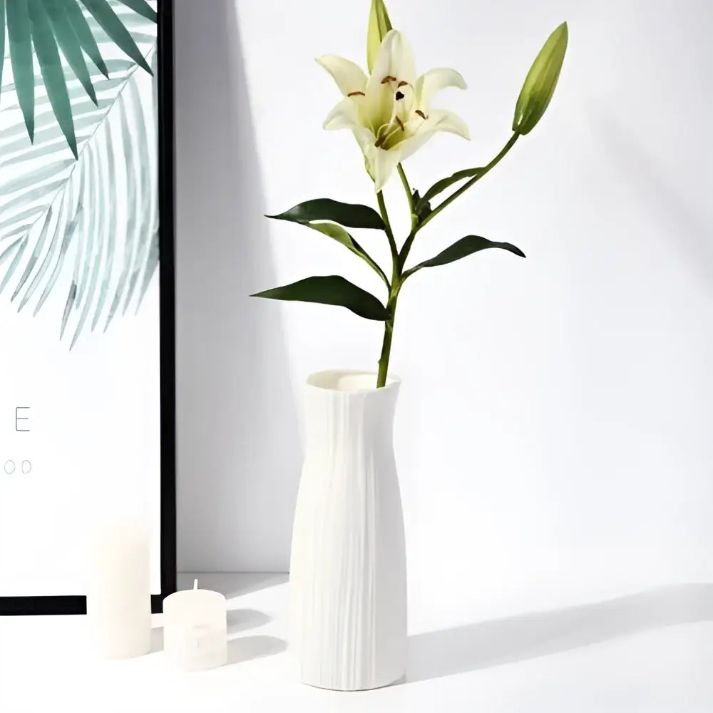 A sleek white nordic plastic vase with vertical ridges holds a single white lily for modern home decor